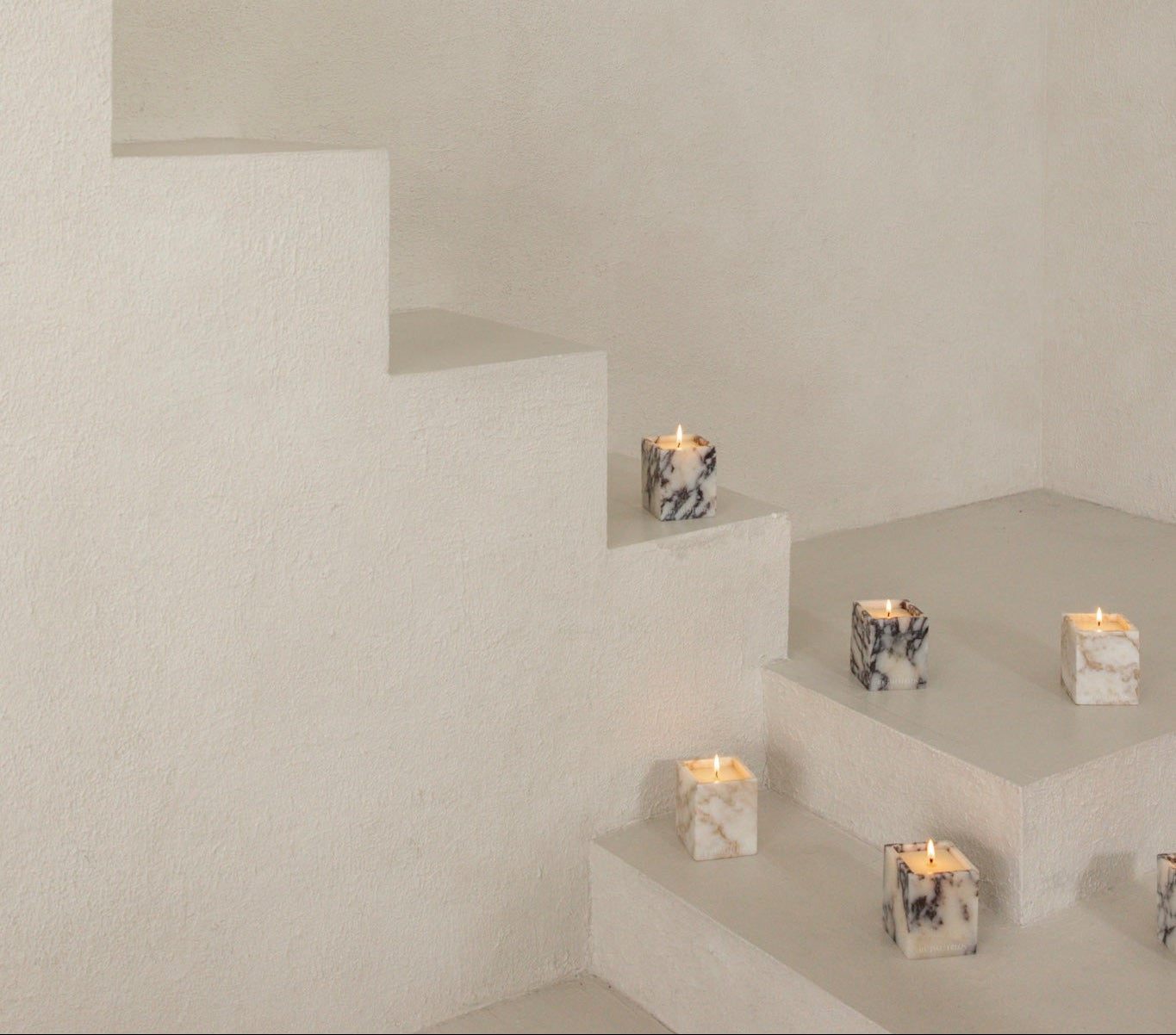 Candles on a minimalist white staircase with a neutral wall background